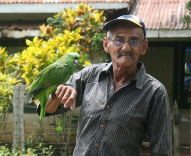 Man in Bolson holds his pet Loro bird, Camille.