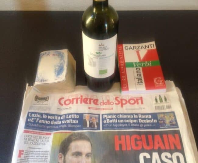 The essential tools of learning Italian: an Italian dictionary (notice how well worn), an Italian verb book, an Italian newspaper and the first of many bottles of Italian wine.