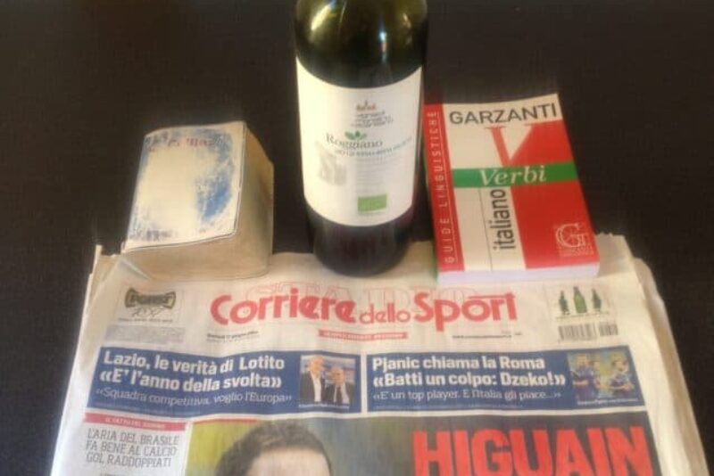 The essential tools of learning Italian: an Italian dictionary (notice how well worn), an Italian verb book, an Italian newspaper and the first of many bottles of Italian wine.