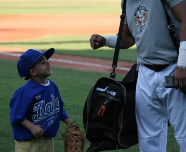 A young fan gets a fist bump from a member of the Italian Baseball League All-Star Team.