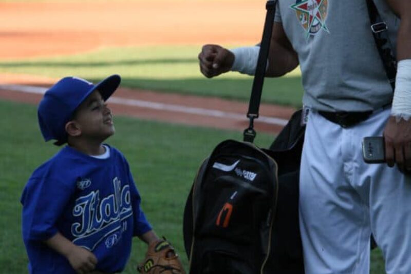 A young fan gets a fist bump from a member of the Italian Baseball League All-Star Team.