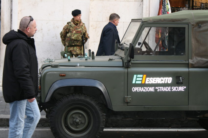 A soldier stands behind a military vehicle near the entrance to the Vatican.