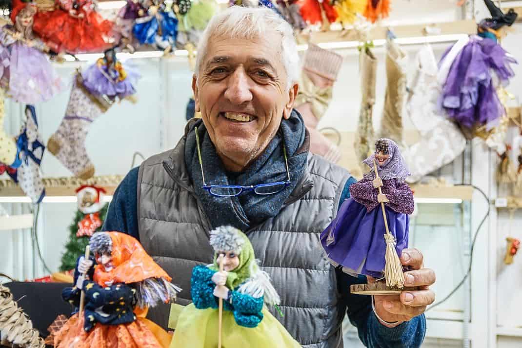 Artist Alberto Levis holds up a befana, a traditional Italian Christmas symbol, at the Piazza Navona Christmas market, the most historic Rome Christmas market.