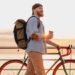 young bearded man traveling on bicycle at sunset sea