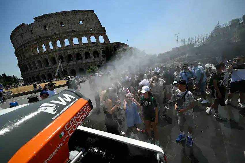 A water spritzer sprays tourists by Rome's Colosseum.